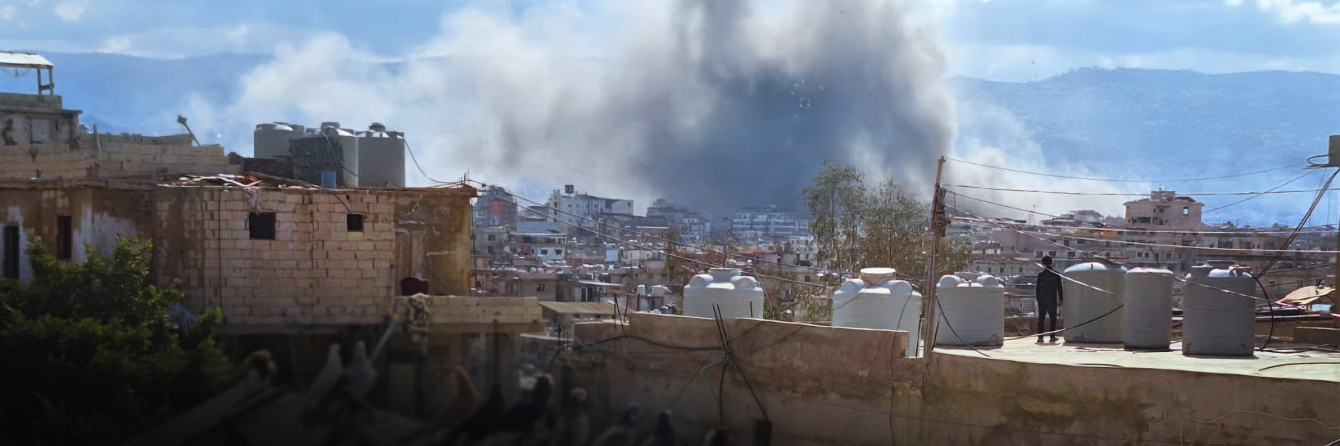 A child on a rooftop watches smoke rise from an explosion in Beirut, Lebanon