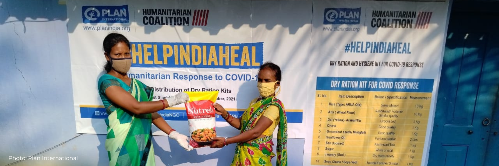 Two women show the bag of food rations distributed to COVID survivors in India