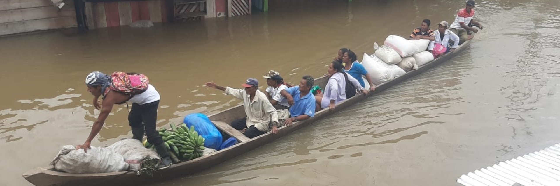 People escape in a boat as their homes are washed away by flooding caused by a hurricane