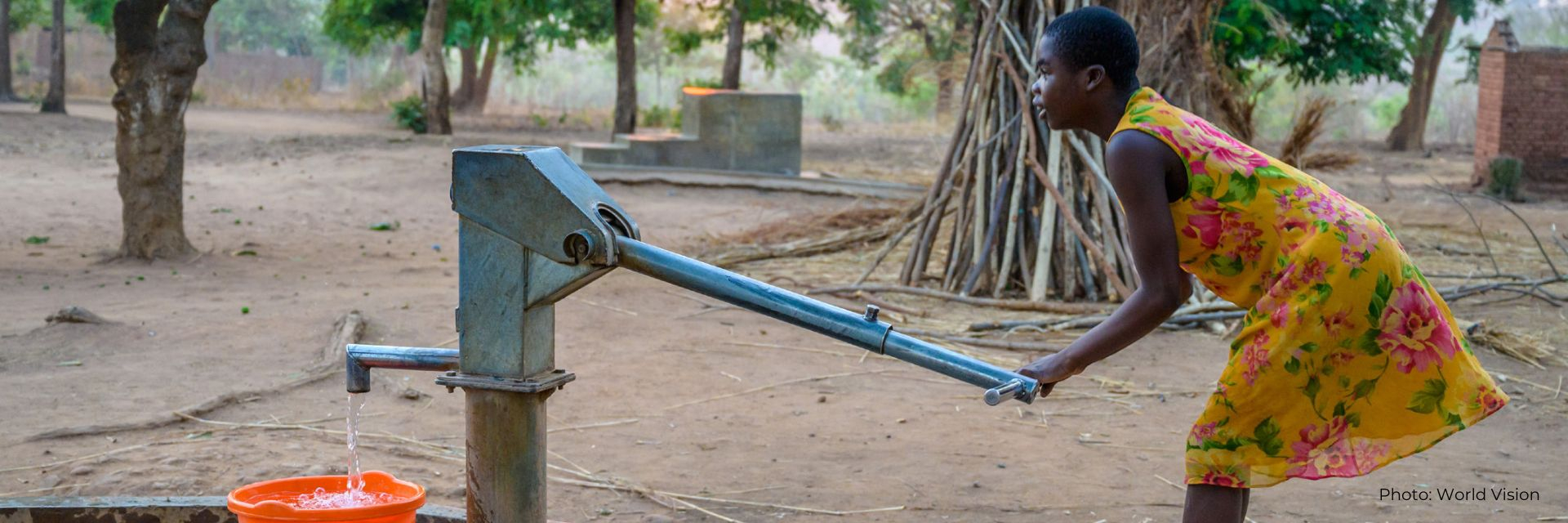 A girl demonstrates using a pump at a new borehole