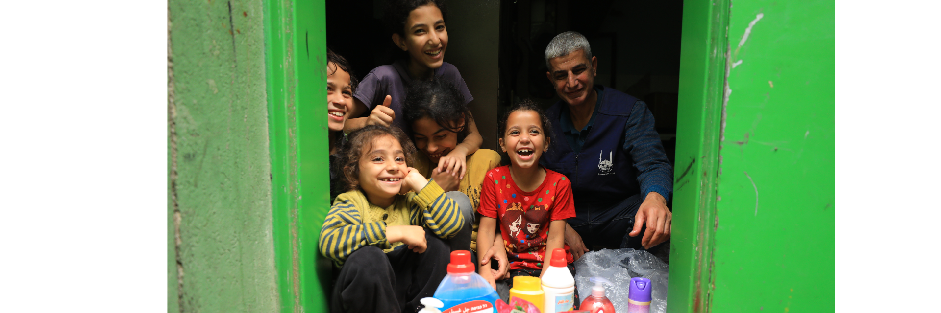 Children laugh. New hygiene products are visible in the foreground.