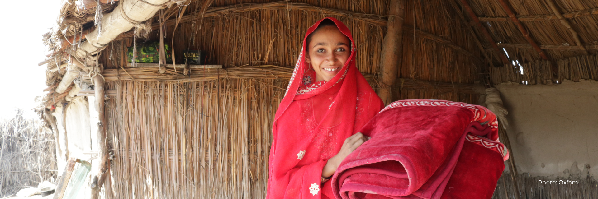 Young woman holds up blanket in front of wall with water marks