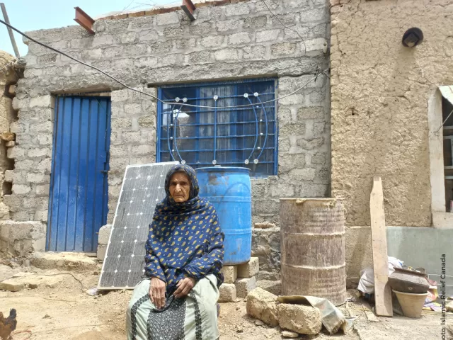 Woman in Pakistan next to her restored house