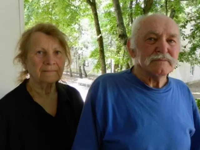 An elderly couple stand side by side