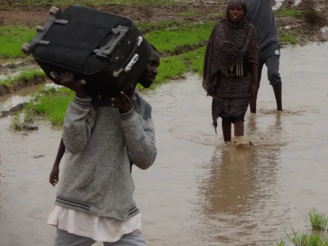 A man carries a suitcase through floodwater in Sudan