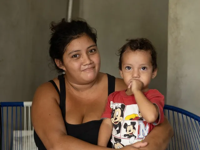 A young mother holds her children after hurricanes destroyed their home
