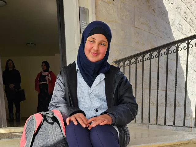 Lana on the steps of the education centre, with her mother Fatouma standing behind her.