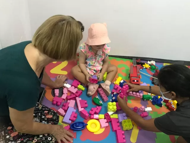 Two women play with young child in Romania