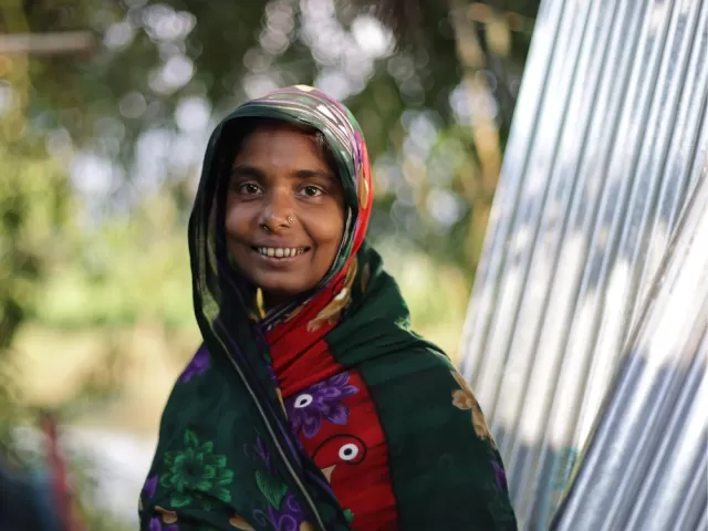 Woman stands beside metal sheeting and smiles at the camera