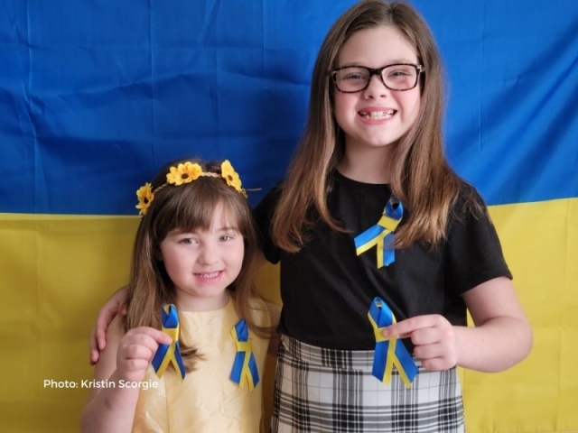 Bella and Poppy holding blue and yellow ribbons