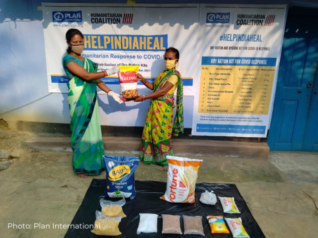 Two women show the bag of food rations distributed to COVID survivors in India