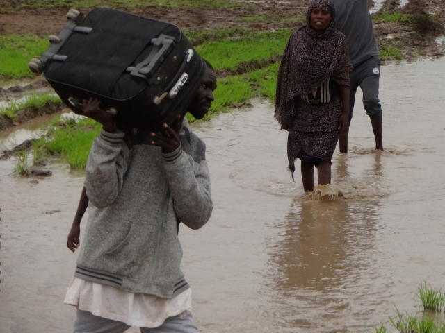 A man carries a suitcase through floodwater in Sudan