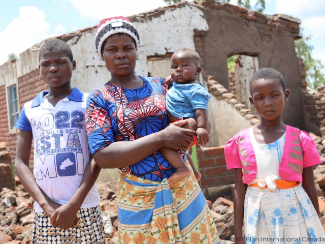 Woman and children in front of damaged home