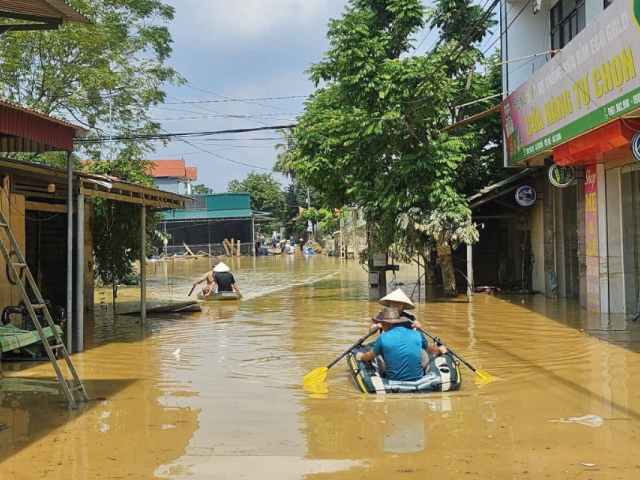 People in inflatable boats paddle down a flooded street in Vietnam