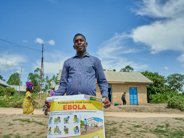 A man holding a poster that reads: "Let's protect ourselves against Ebola" in French.